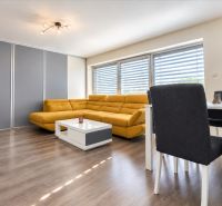 Wohnzimmer mit Holzdekorboden, gelbem Sofa und Esstisch.