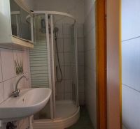 Ein Badezimmer in einem Einfamilienhaus mit weißen Fliesen und einer Duschkabine.