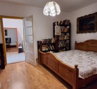 Ein Schlafzimmer in einem Einfamilienhaus mit einem Boden in Holzoptik, einem großen Bett und einer Lampe.