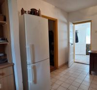 Eine Küche in einem Einfamilienhaus mit einem weißen Kühlschrank und Holzmöbeln.