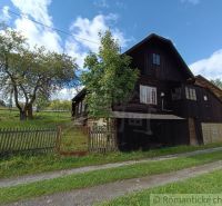 Eine Holzhütte in Staškov, umgeben von Bäumen und einem Zaun auf einer geräumigen grünen Fläche.
