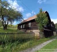 Eine Holzhütte in Staškov, umgeben von Gras und Bäumen hinter einem Zaun.