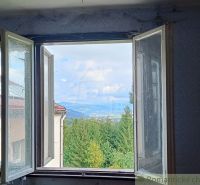 Der Blick von der Hütte auf die Berge und Wälder in Staškov durch das offene Fenster.