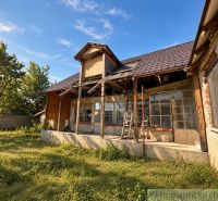 Ein Einfamilienhaus in Vištuk mit einer Veranda in Renovierung, umgeben von Grün und Bäumen.