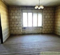 Ein Zimmer mit Tapeten und einem Holzboden, beleuchtet durch ein großes Fenster.
