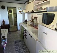 Eine Küche in einer Hütte mit weißen Schränken und Geräten, neben einem Badezimmer.
