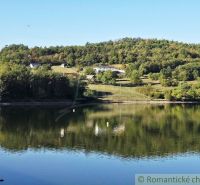 Ein Blick auf den Teich mit Bäumen und Hügeln in den Gärten in Krupina.