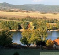 Ein See, umgeben von Herbstbäumen und Hügeln in den Gärten von Krupina.