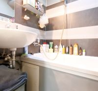 Badezimmer in einer 2-Zimmer-Wohnung mit Waschbecken und Badewanne, genutzter Stauraum für Kosmetik.