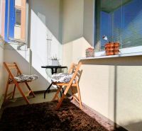 Balkon mit zwei Klappstühlen und einem Teppich in einer 2-Zimmer-Wohnung.