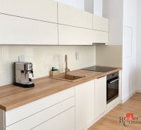 Küche in einer Einzimmerwohnung mit Holzdekorboden, cremefarbene Schränke, Kaffeemaschine.