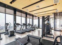 Ein Fitnessstudio mit Aussicht, ausgestattet mit Laufbändern und Kraftgeräten. Wohnungsbau.