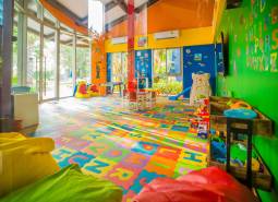 Ein farbenfroher Indoor-Spielplatz im Inneren eines Wohnbauprojekts mit Spielzeug und Tischen.