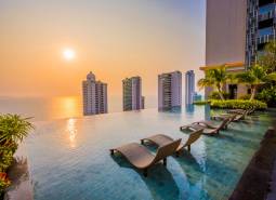Schwimmbad, Liegestühle und Panorama des Wohnungsbaus in Pattaya bei Sonnenuntergang.