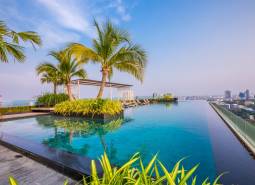 Infinity-Pool und Palmen auf dem Dach mit Blick auf die Skyline von Pattaya, Wohnungsbau.