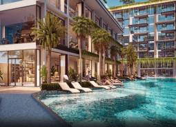 Wohnungsbau in Pattaya mit Pool und Liegestühlen, umgeben von Palmen und Pflanzen.