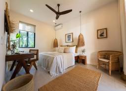 Helles Schlafzimmer mit Hängelampen und Korbmöbeln in einem Einfamilienhaus.