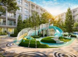 Spielplatz bei einem Wohnungsbauprojekt in Phuket mit großer Rutsche und viel Grün.