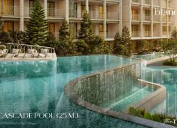 Ein Pool mit Kaskaden beim Bau von Wohnungen in Phuket mit Liegestühlen und Grünflächen.