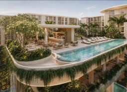 Wohnungsbau in Pattaya mit einem Pool auf der Terrasse, umgeben von üppigem Grün und Liegestühlen.