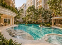 Luxuriöser Pool mit Liegestühlen, umgeben von Grünflächen, beim Bau von Wohnungen in Pattaya.