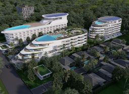 Wohnungsbau in Phuket mit wellenförmigem Design und Dachpools, eingebettet in Grün.