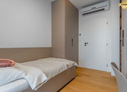 Einzelzimmer mit Bett, Einbauschrank und Boden mit Holzdekor.