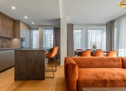 Innenraum mit Holzboden, orangefarbenem Sofa und Esstisch. Wohnungsbau.