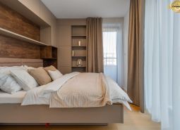 Helles Schlafzimmer mit beigen Vorhängen, Regalen und einem Boden mit Holzdekor im Projekt Wohnungsbau.