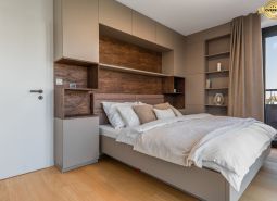 Schlafzimmer in einer Wohnung mit modernen Schränken und einem Boden in Holzoptik.