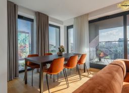 Essbereich mit orangefarbenen Stühlen, Holzboden, Zugang zum Balkon. Wohnungsbau.