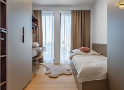 Minimalistisches Zimmer mit Bett, Schreibtisch und Boden in Holzoptik. Wohnungsbau.