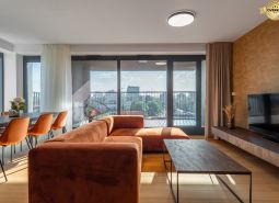 Wohnzimmer mit orangefarbenem Sofa, Esstisch und Blick auf die Stadt. Wohnungsbau.