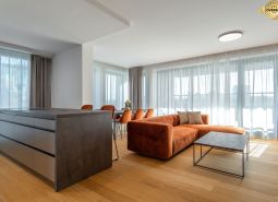 Wohnzimmer mit einem orangefarbenen Sofa, einem Boden in Holzoptik und einem Tisch im Wohnzimmer.