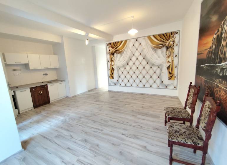 Innenraum einer Einzimmerwohnung mit Kochnische, Zierwand und Parkettboden.