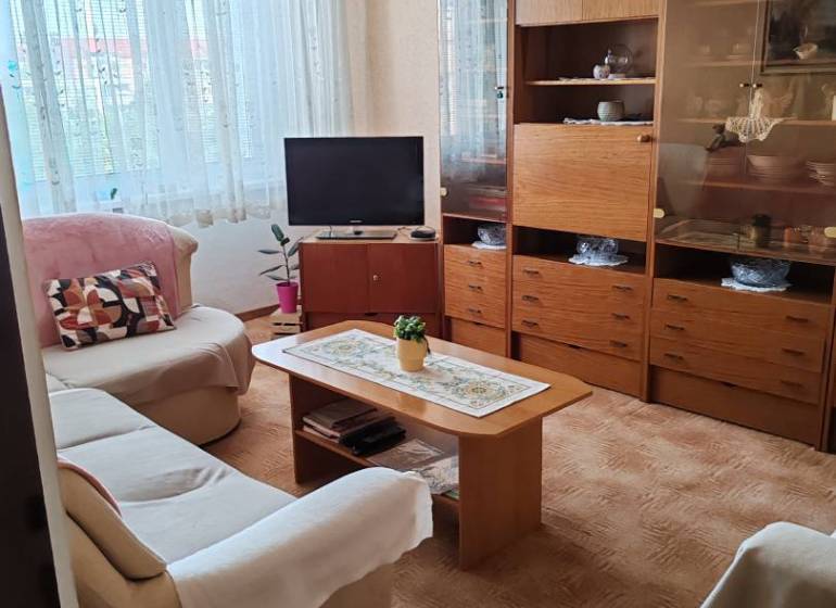 Wohnzimmer mit Sofa, Fernseher und Holzschrank in einer 3-Zimmer-Wohnung.