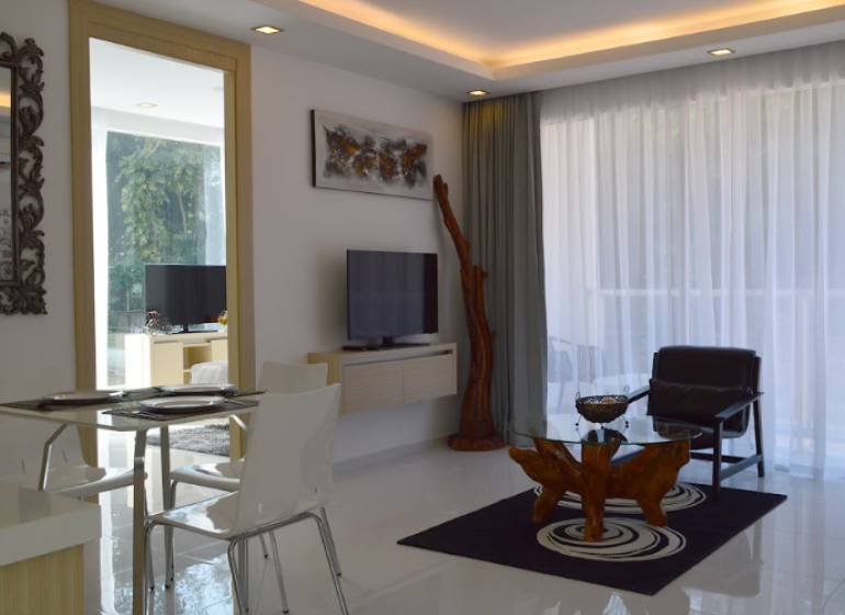 Innenraum einer 2-Zimmer-Wohnung mit Wohnzimmer, Esstisch und Fernseher.