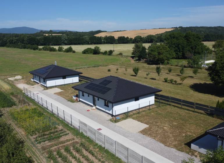 Einfamilienhäuser in Podlužany mit modernen Dächern und Sonnenkollektoren auf dem Feld.