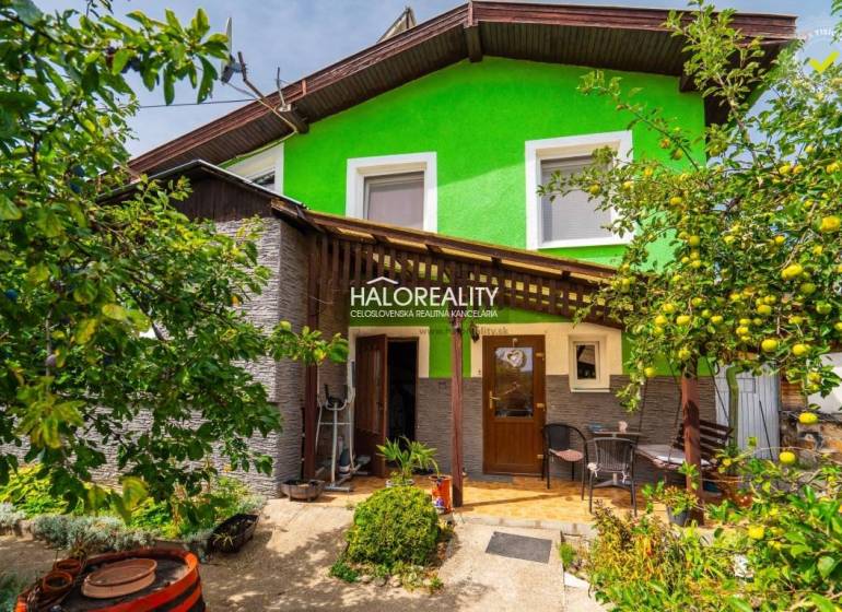 Ein Einfamilienhaus in Banská Štiavnica mit einer Holzveranda, umgeben von Grün und Obstbäumen.