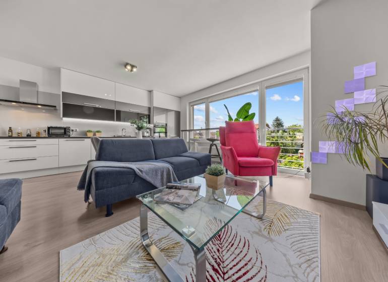 Wohnzimmer mit Sofa und Sessel in einer 4-Zimmer-Wohnung. Große Fenster mit Aussicht.