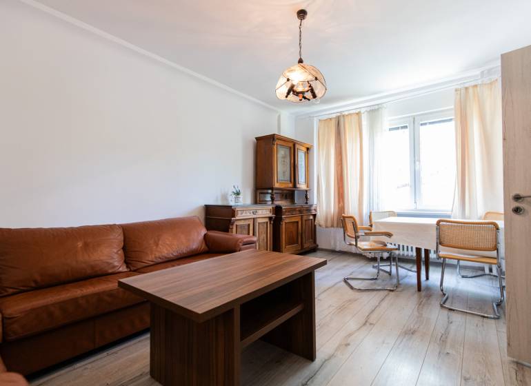 Wohnzimmer mit Sofa, Holztisch und Stühlen in einer 4-Zimmer-Wohnung.