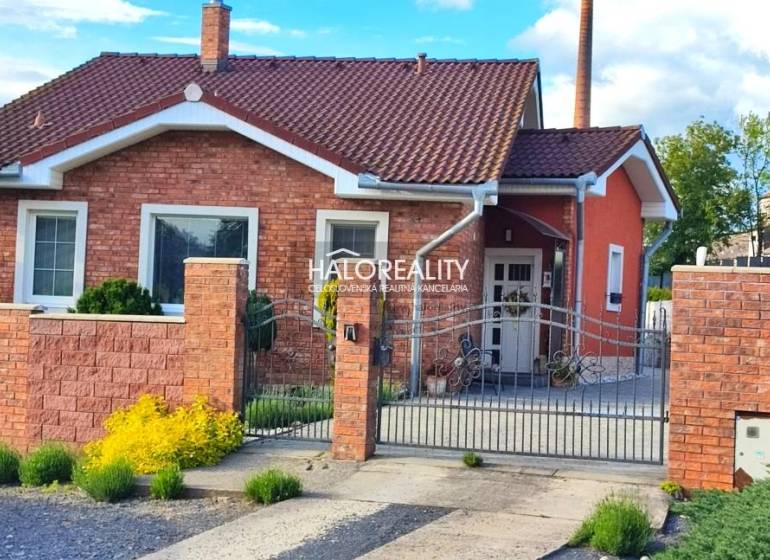 Ein Einfamilienhaus in Kalinovo mit einer Ziegelfassade, einem dekorativen Zaun und Gartenelementen.