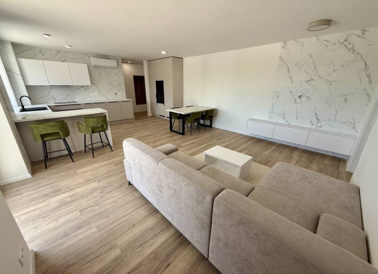 Geräumiges Wohnzimmer mit Küche, Esstisch und Sofa in einer 2-Zimmer-Wohnung.