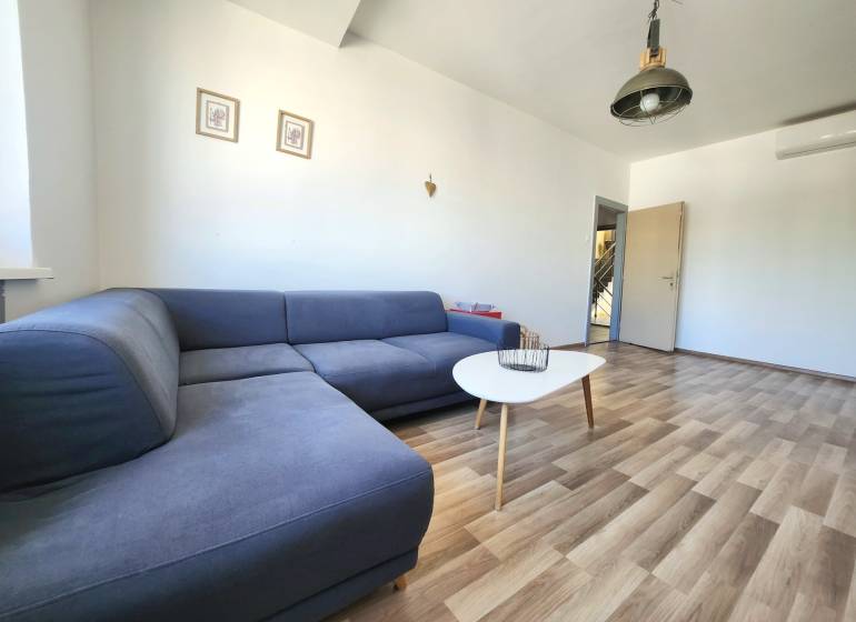 Wohnzimmer mit einem blauen Sofa, einem Tisch und Holzboden in einer 2-Zimmer-Wohnung.