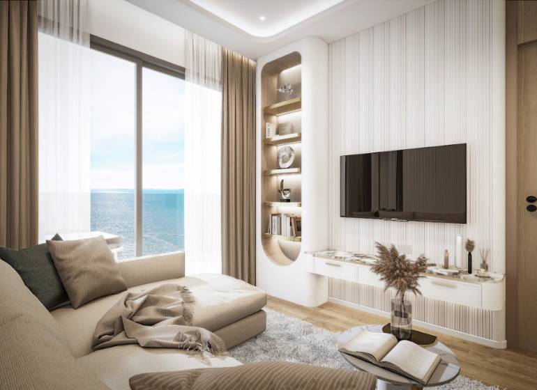 Wohnzimmer in einer 3-Zimmer-Wohnung mit Meerblick, bequeme Couch, Fernseher an der Wand.