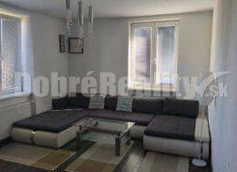 Wohnzimmer in einer 2-Zimmer-Wohnung mit großem Sofa und Fenster.