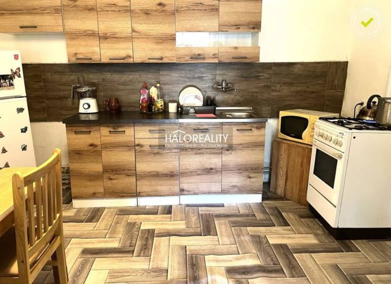 Küche in einem Einfamilienhaus mit Holzschränken, Herd und Kühlschrank.