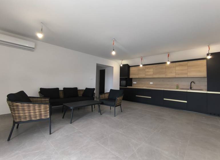 Wohnbereich einer 4-Zimmer-Wohnung mit dunklen Möbeln und einer Küche mit Holzelementen.