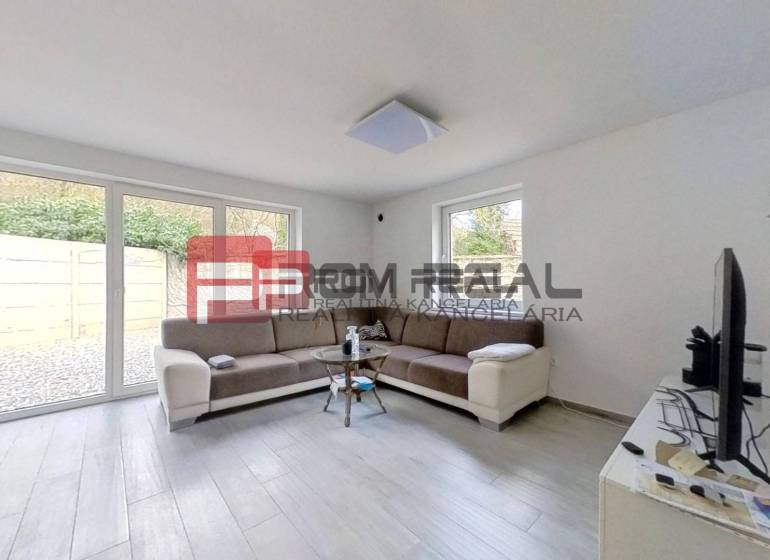 Wohnzimmer in einem Einfamilienhaus mit Sofa, Fenstern und Fernseher.