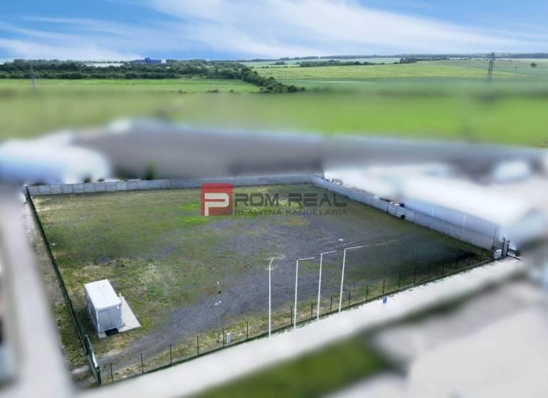 Produktionsräume in Pezinok mit eingezäuntem Außenbereich und Container, umgeben von Feldern.